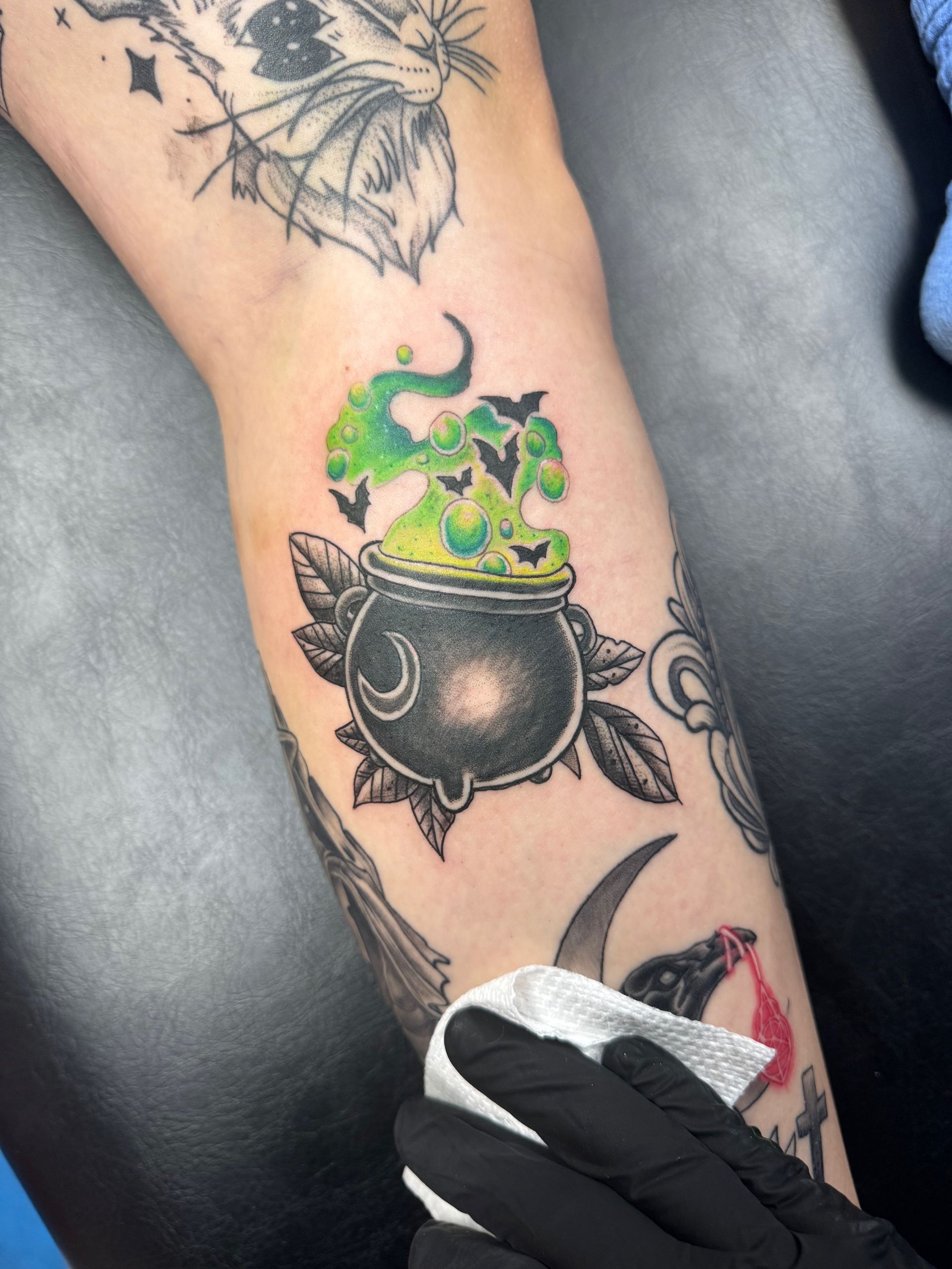 A person has a cauldron tattoo on their arm