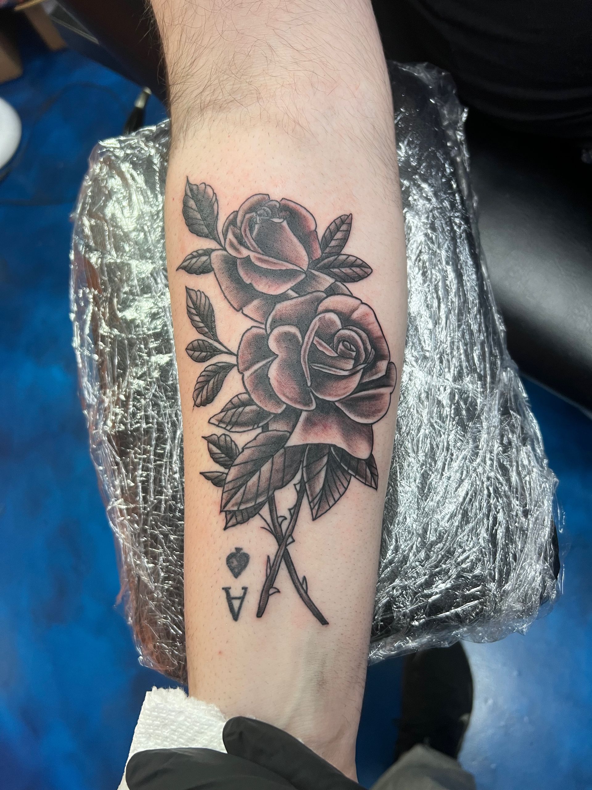 A person has a tattoo of two roses on their forearm