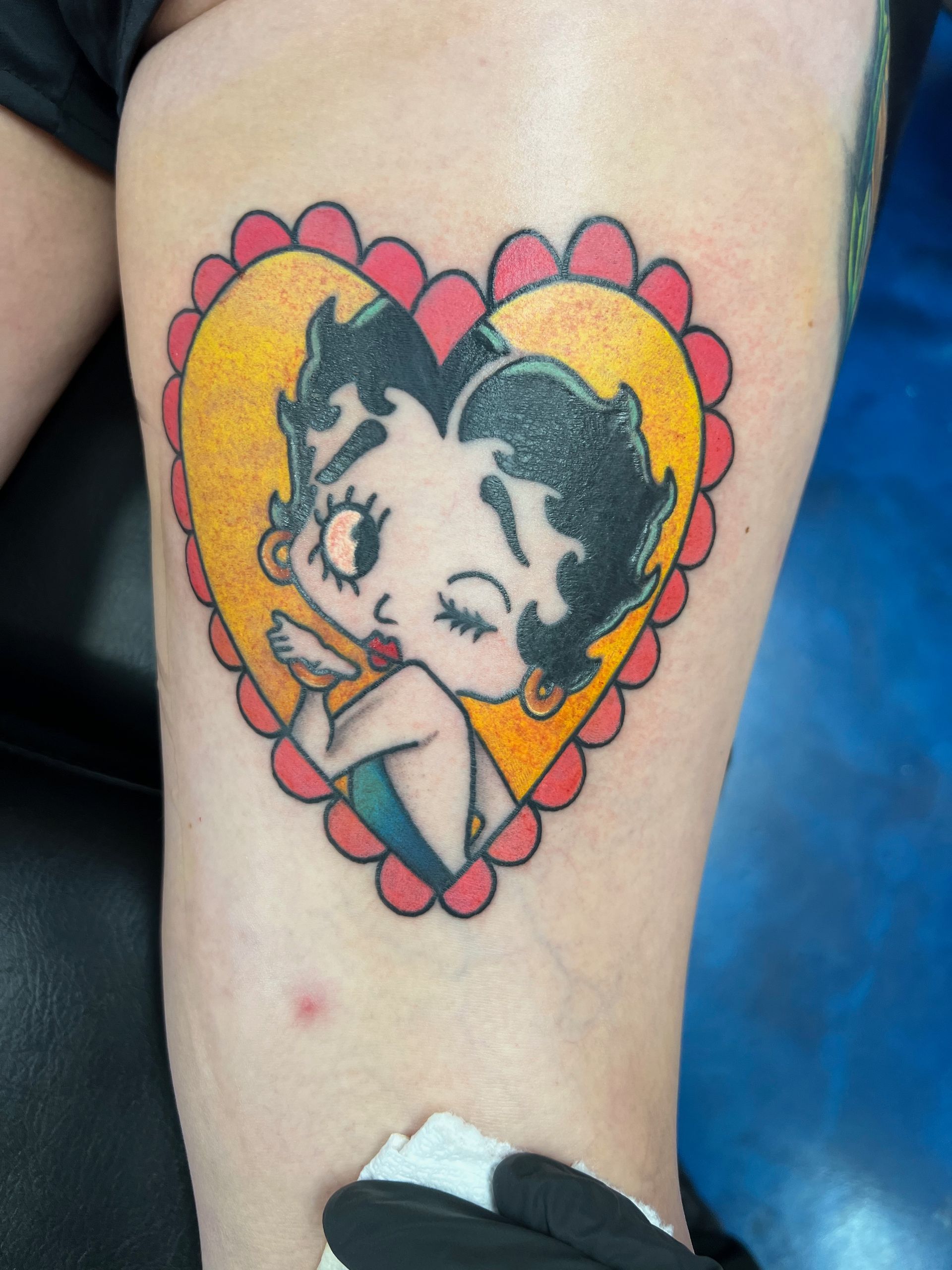 A woman has a tattoo of betty boop in a heart