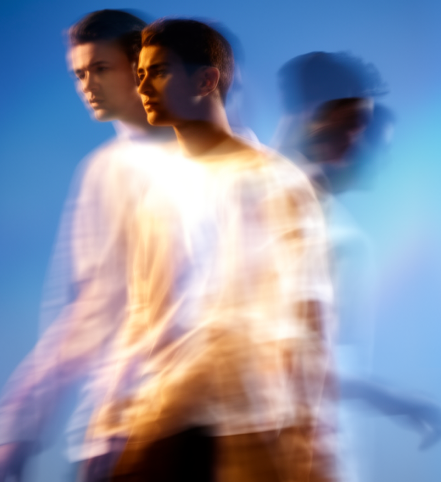 Motion-blurred figure in white shirt against a blue background, creating a layered, ghosted effect
