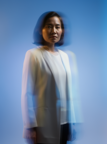 Blurred portrait of a person in a white blazer against a blue background