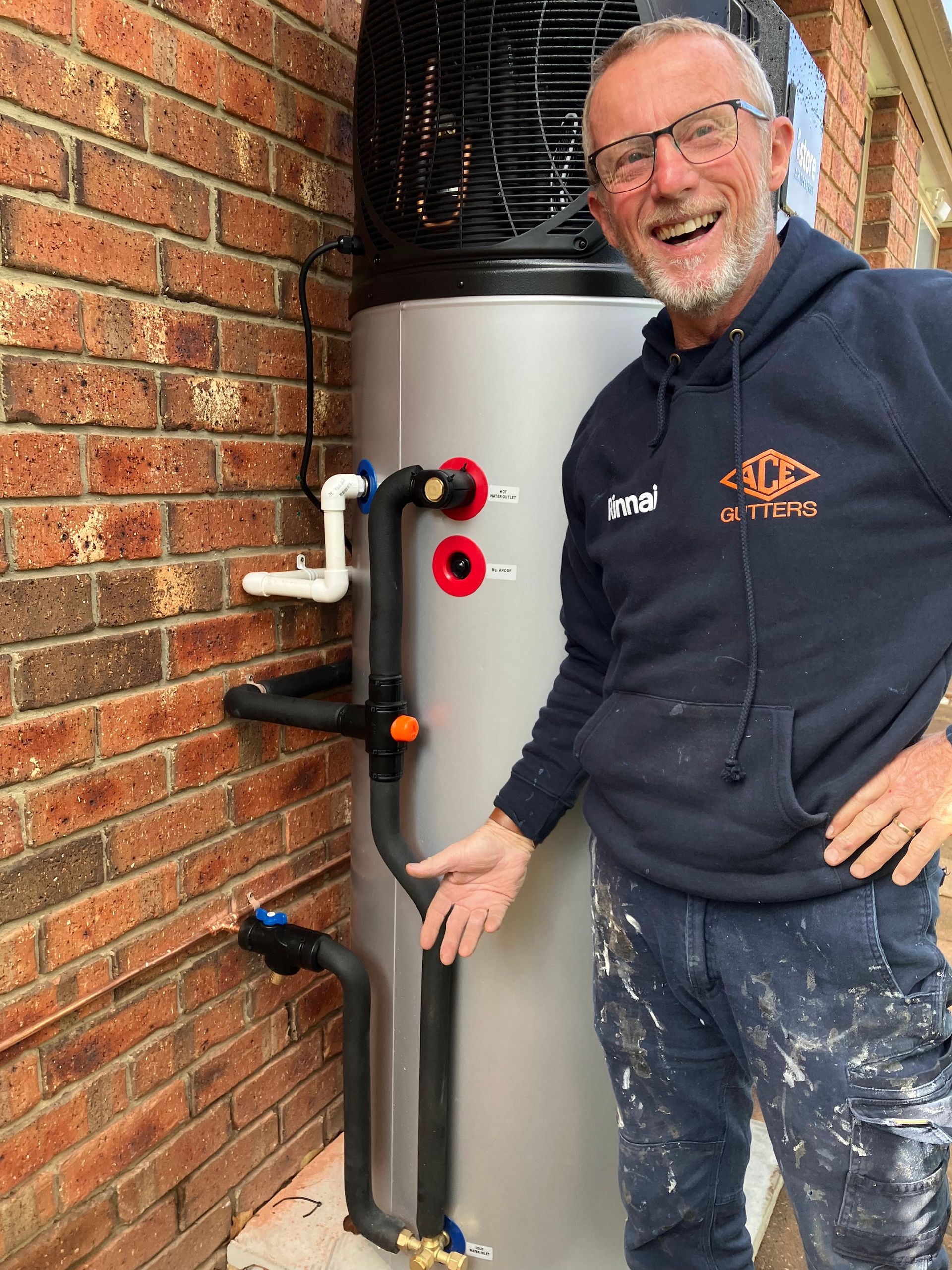 Man standing beside a wall-mounted water filtration system next to a brick wall — Plumbing in Canberra, ACT