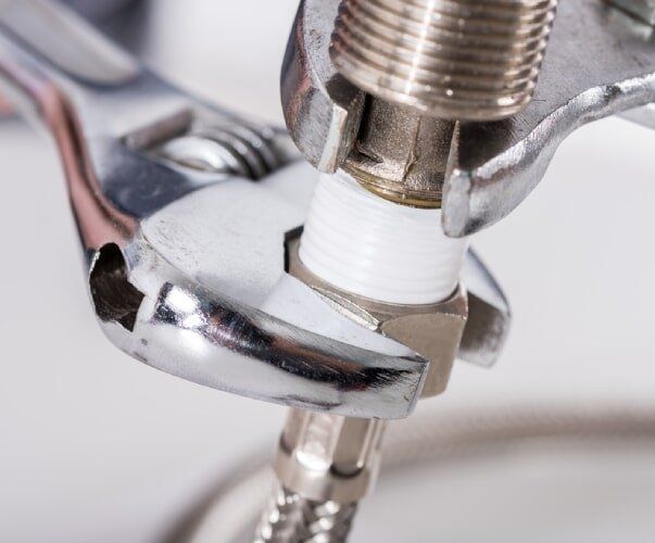 Plumbing Contractor tightening loose tap with silver wrench