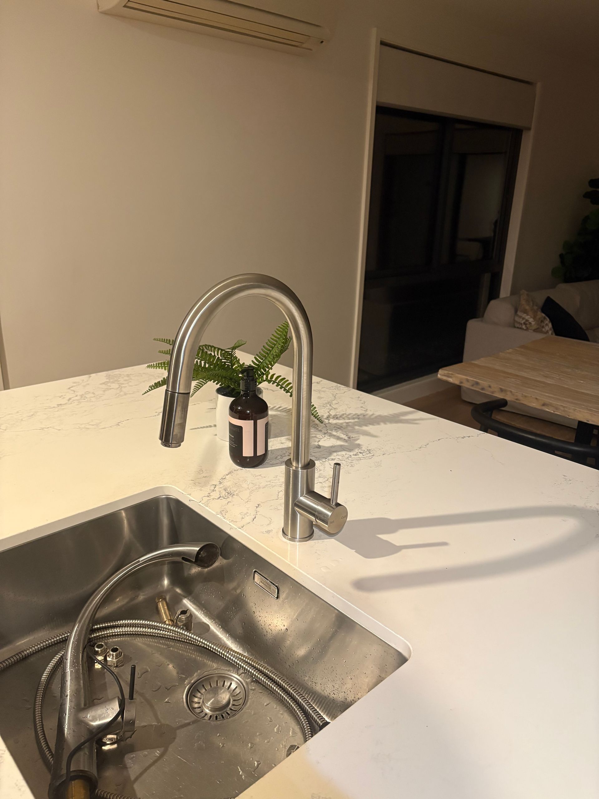 Kitchen sink with modern chrome faucet on a white countertop in a dimly lit room