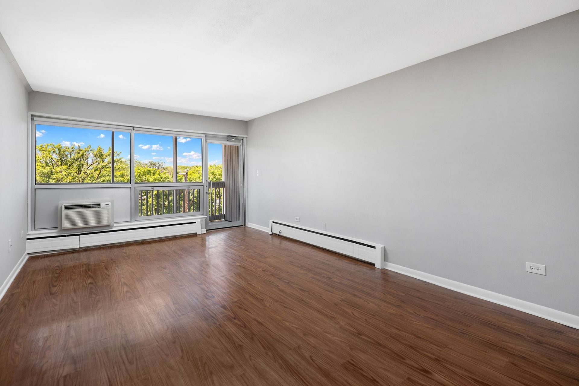 an empty living room with wood floors and a window
