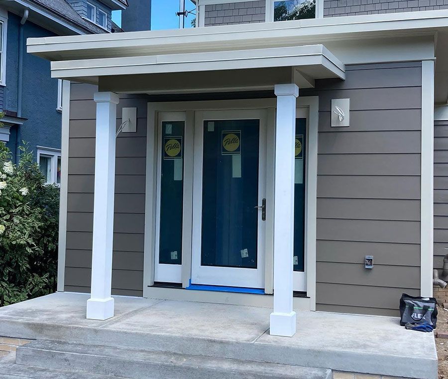 Front entrance with double blue doors, white columns, and a small covered porch on a gray house