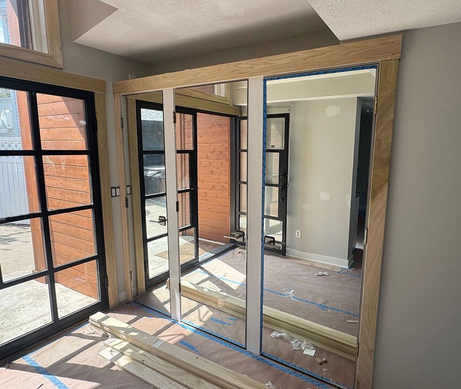 Small room with mirrored closet doors, a window, and sunlight casting shadows on the floor.