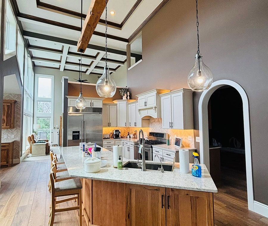 Bright modern kitchen with a large island, pendant lights, wood beams, and an arched doorway