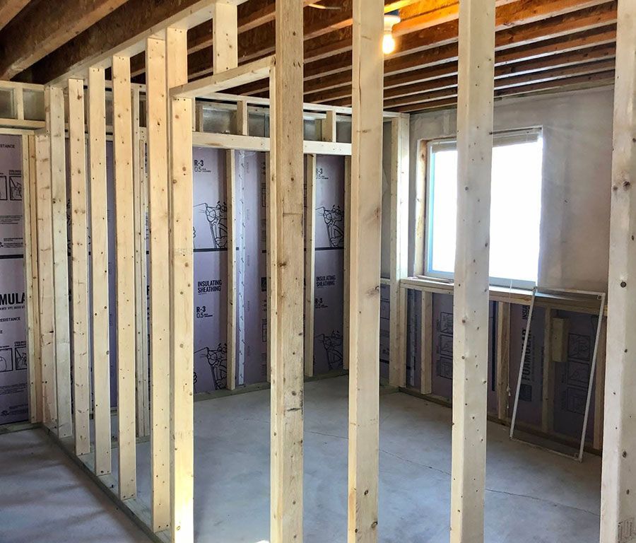 Framed interior room under construction with exposed studs, insulation, and windows