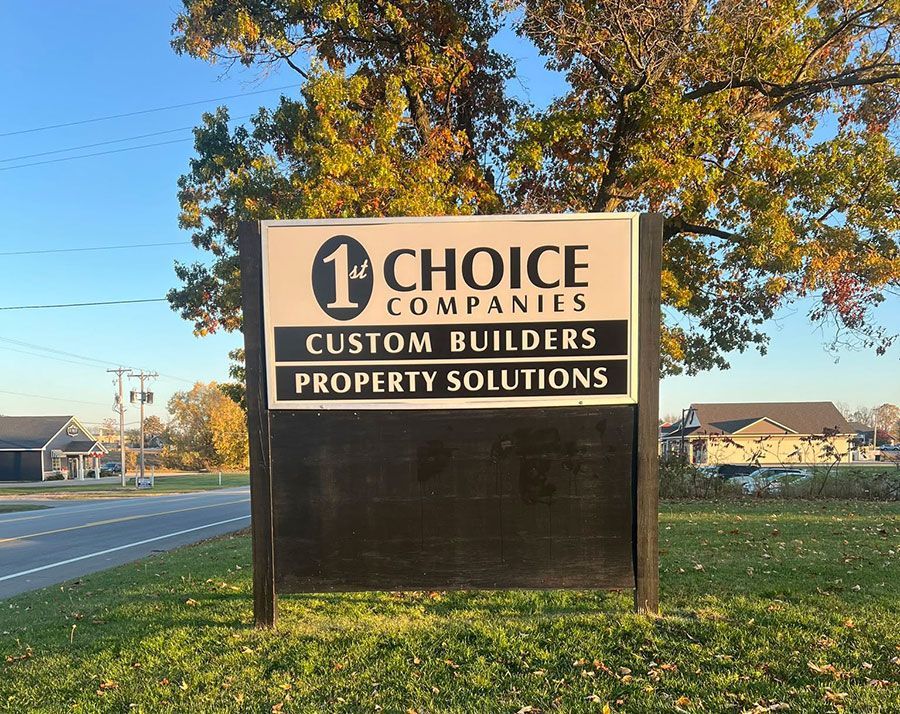 Roadside sign for Choice Companies: Custom Builders and Property Solutions, with autumn trees and grassy field.