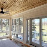 Bright sunroom with wood ceiling, ceiling fan, and large windows and glass doors opening to a porch.