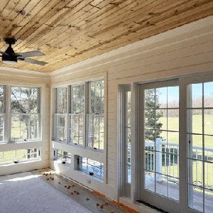 Bright sunroom with wood ceiling, ceiling fan, and large windows and glass doors opening to a porch.