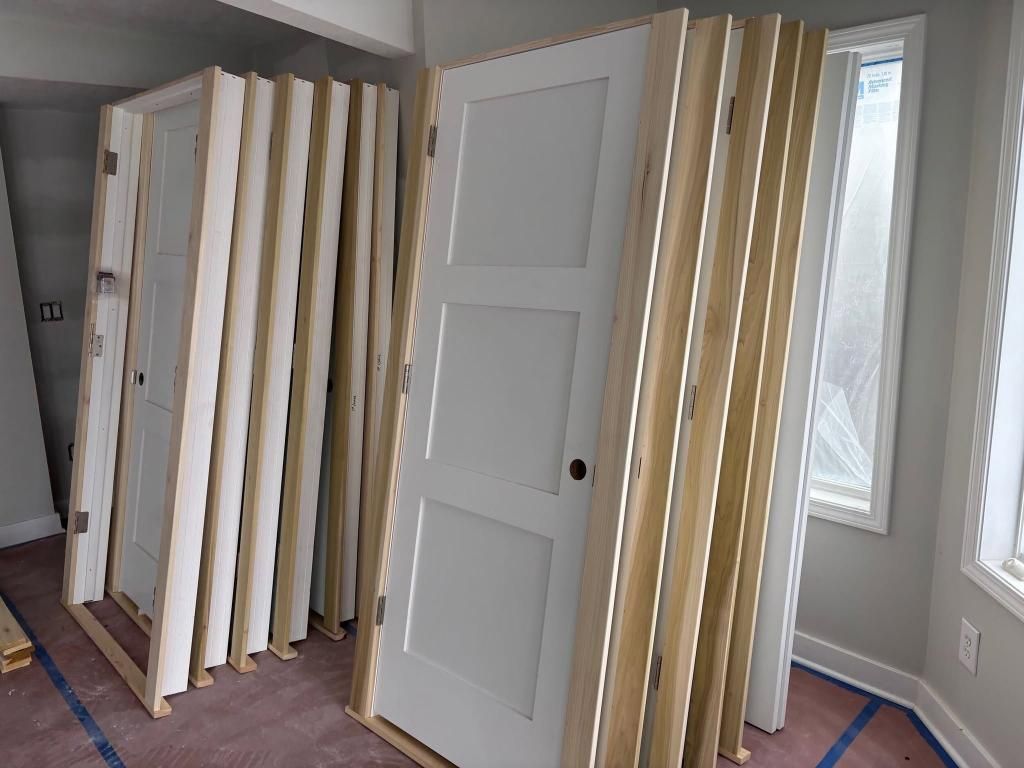Several white doors and beige slatted panels arranged in a room, like storage or display partitions.