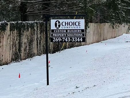 Sign for Choice Companies in snowy yard beside a fence, with phone number 269-743-3344