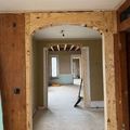 Damaged hallway in an unfinished house, with exposed wood framing and open doorways.