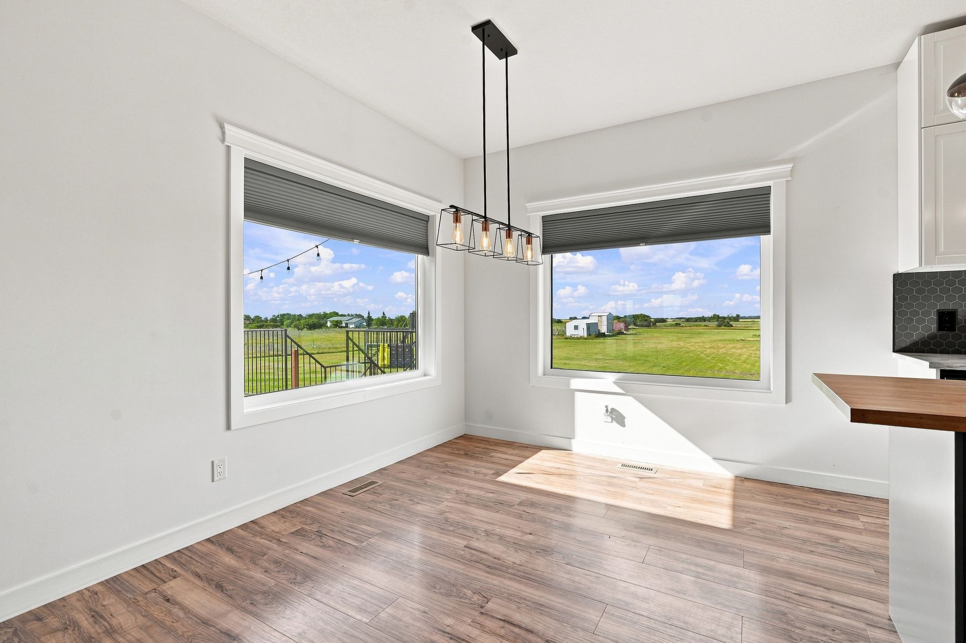 Empty modern room with light wood floors, white walls, and large windows overlooking snowy trees