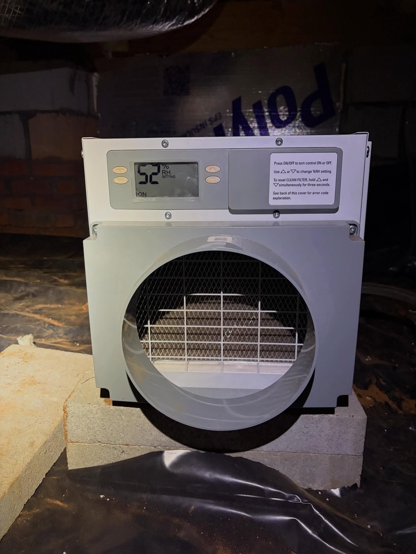 Small white portable fan or heater on a cinder block, with digital display and circular front grille.