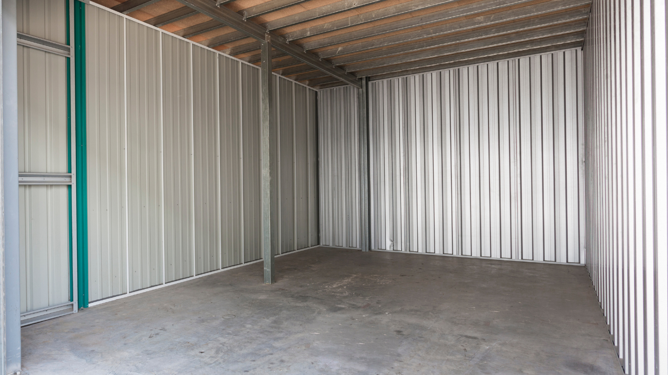 White metal warehouse with several garage doors and one open bay on a gravel lot