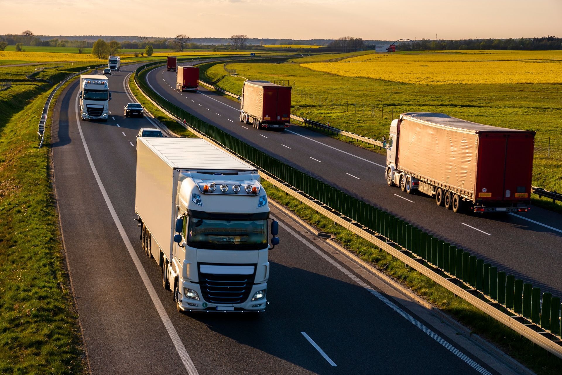 Heavy truck traffic travels along a highway in the evening.