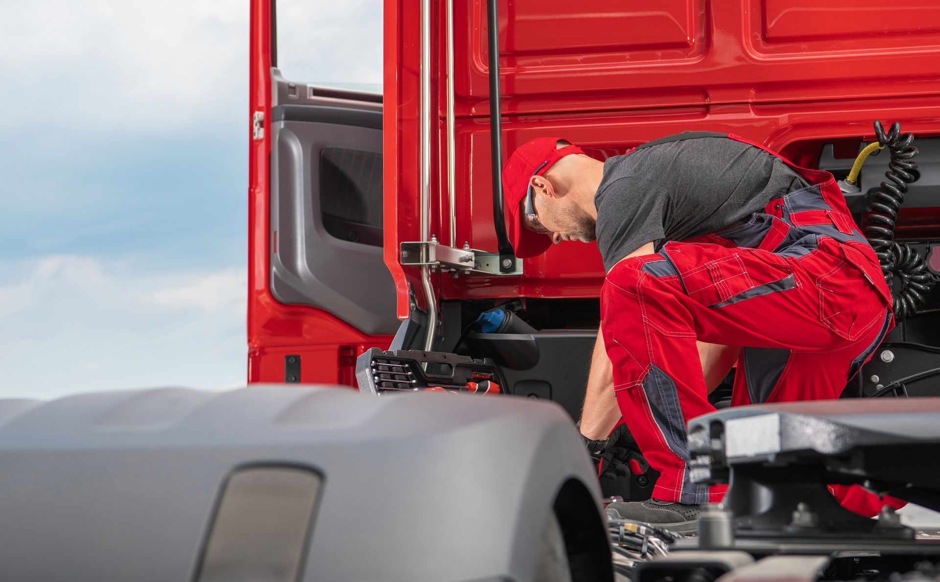 Diesel mechanic inspecting semi truck engine compartment during commercial vehicle repair service.