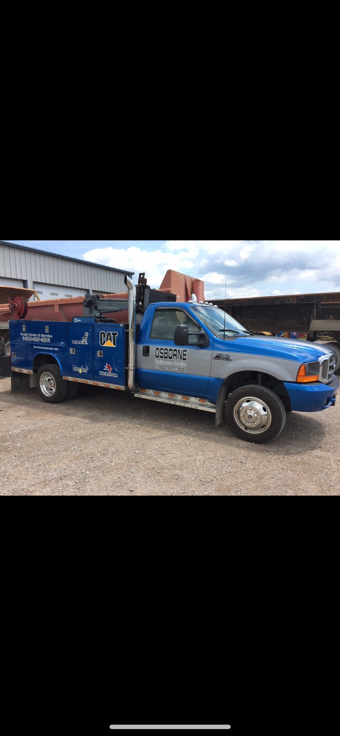 Blue and gray work truck parked on gravel.