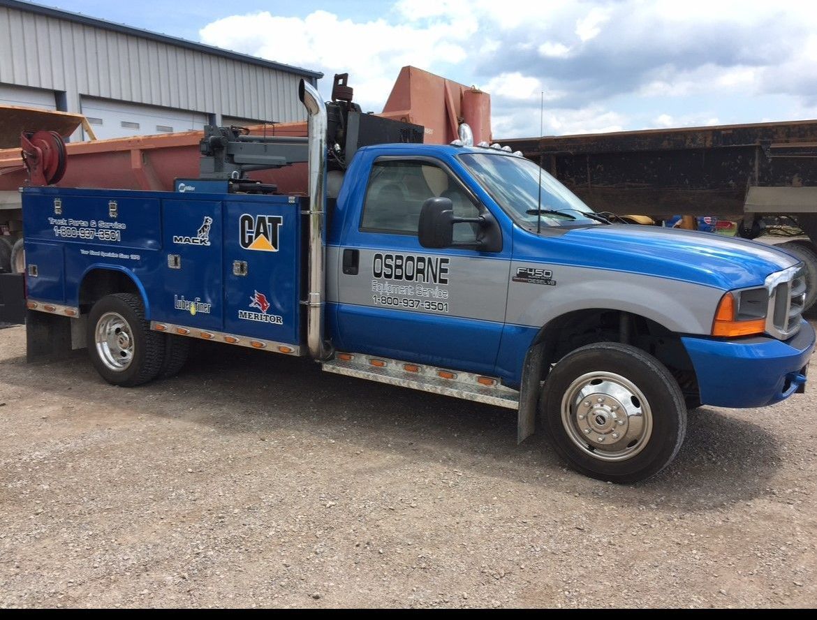 Blue service truck parked on gravel near industrial equipment. Blue service truck parked on gravel near industrial equipment.
