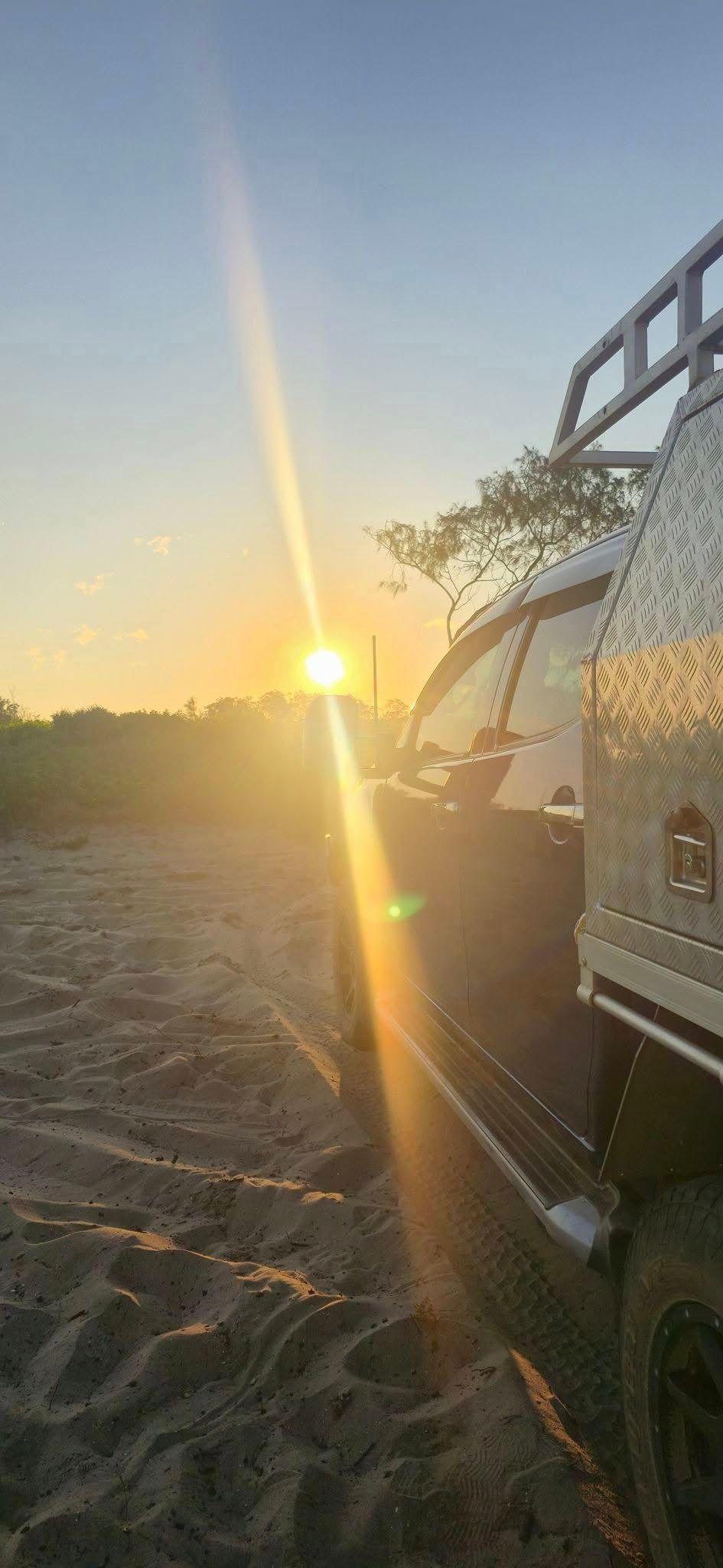 A Vehicle Parked on a Sandy Surface During a Bright, Golden Sunrise — Coast to Country Caravan Repairs In Port Macquarie, NSW