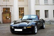 Black convertible sports car parked outside white building