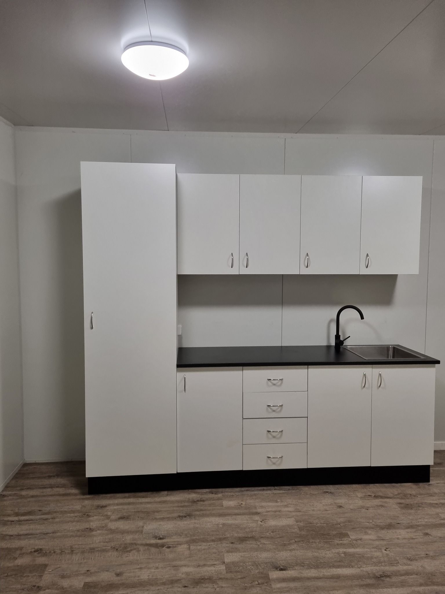 White Kitchen Cabinets With Black Countertop, Sink, and Faucet — Taylormade Constructions & Renovations In Goodger, QLD