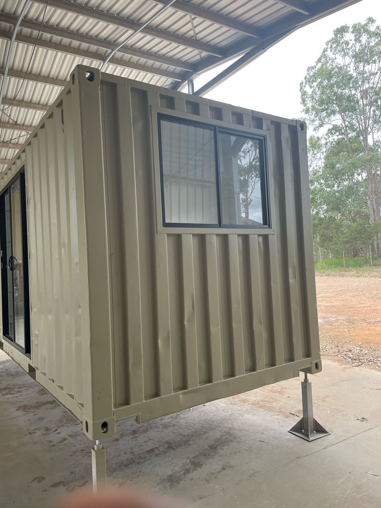 Olive-colored Shipping Container With a Window and Door — Taylormade Constructions & Renovations In Yarraman, QLD