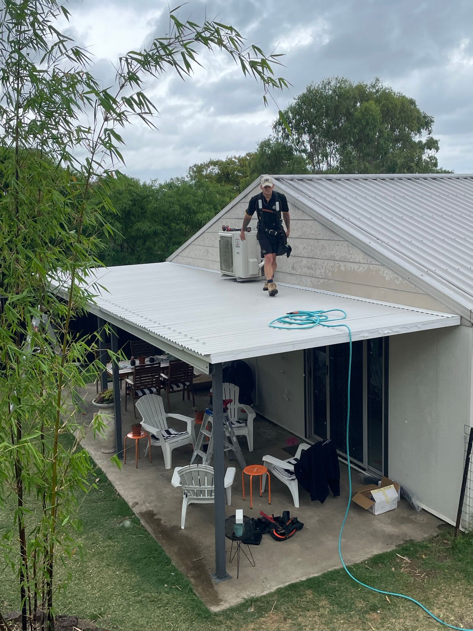 Man Walking on a Metal Roof Near an Air Conditioner — Taylormade Constructions & Renovations In Kingaroy, QLD