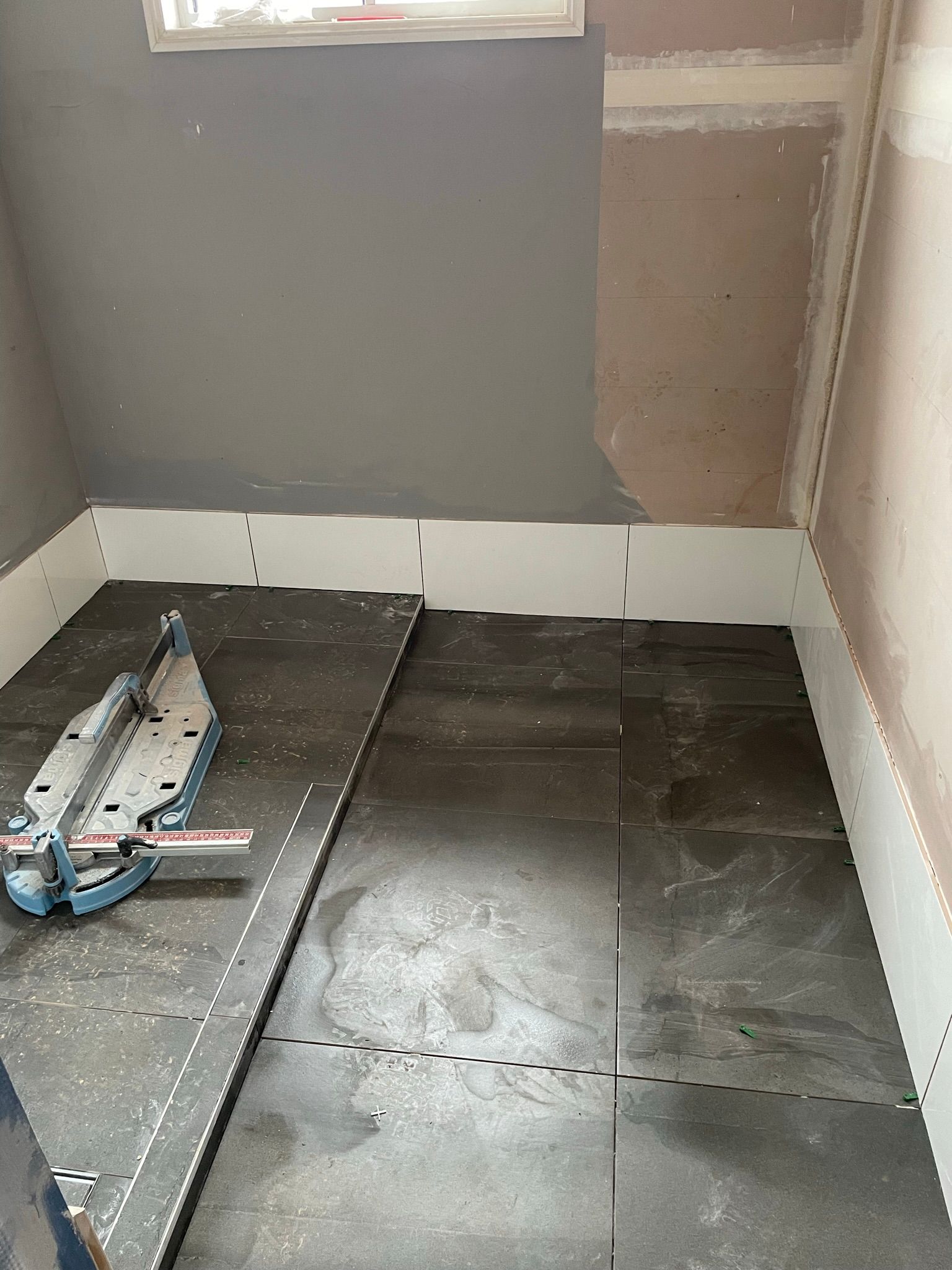 Tiles Being Installed in a Bathroom With a Tile Cutter — Taylormade Constructions & Renovations In Ellesmere, QLD
