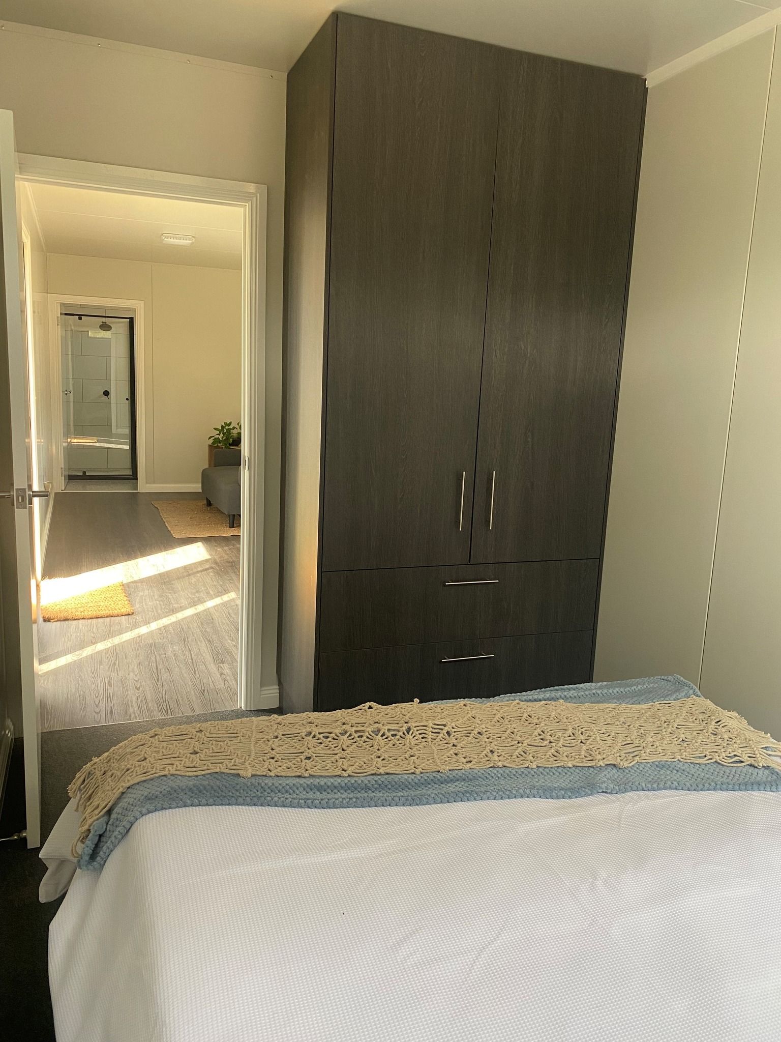 A Bedroom With a Tall Wardrobe and Bed With White Cover — Taylormade Constructions & Renovations In Kingaroy, QLD