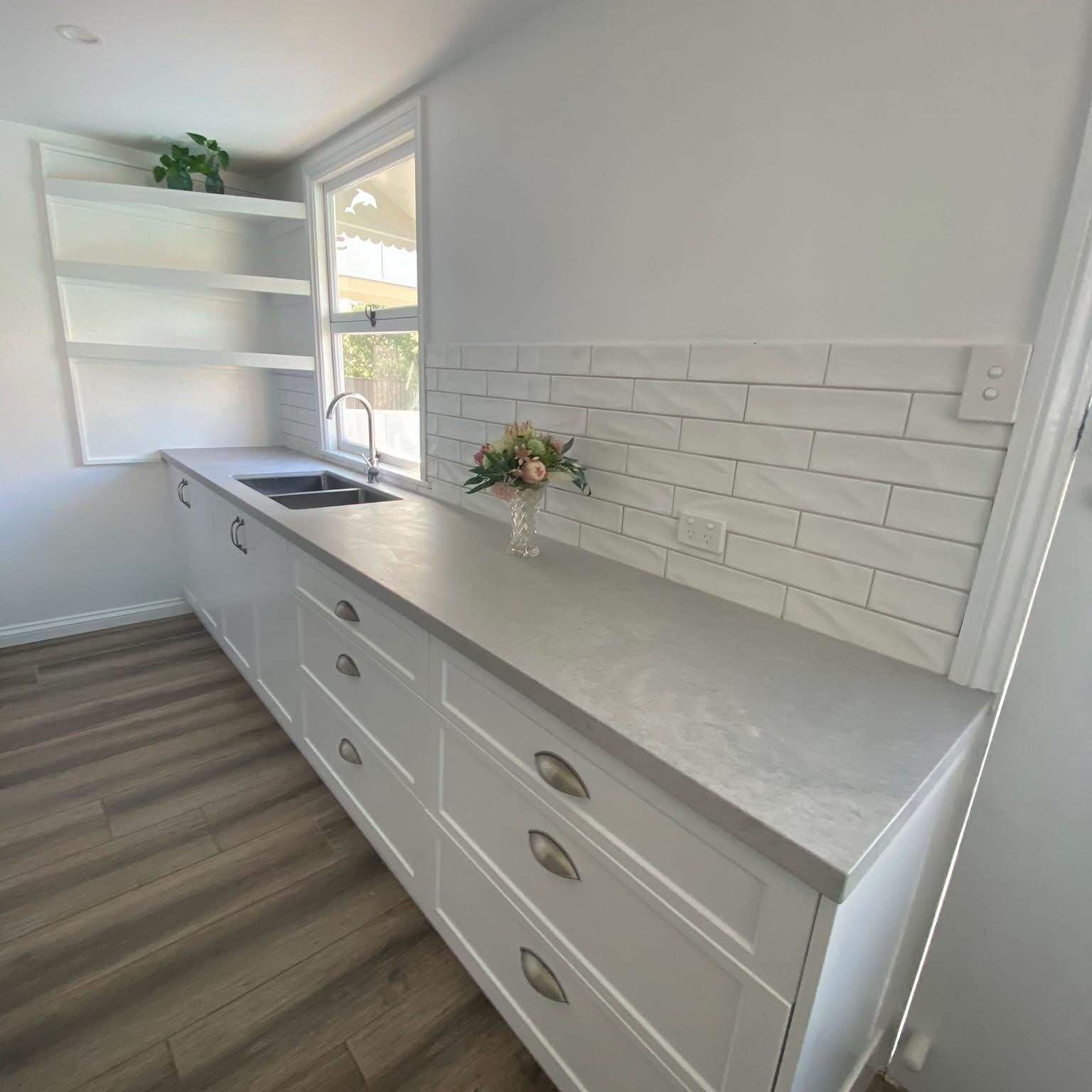 White Kitchen With Grey Countertop, Sink, Window, and Flower Vase — Taylormade Constructions & Renovations In Tarong, QLD