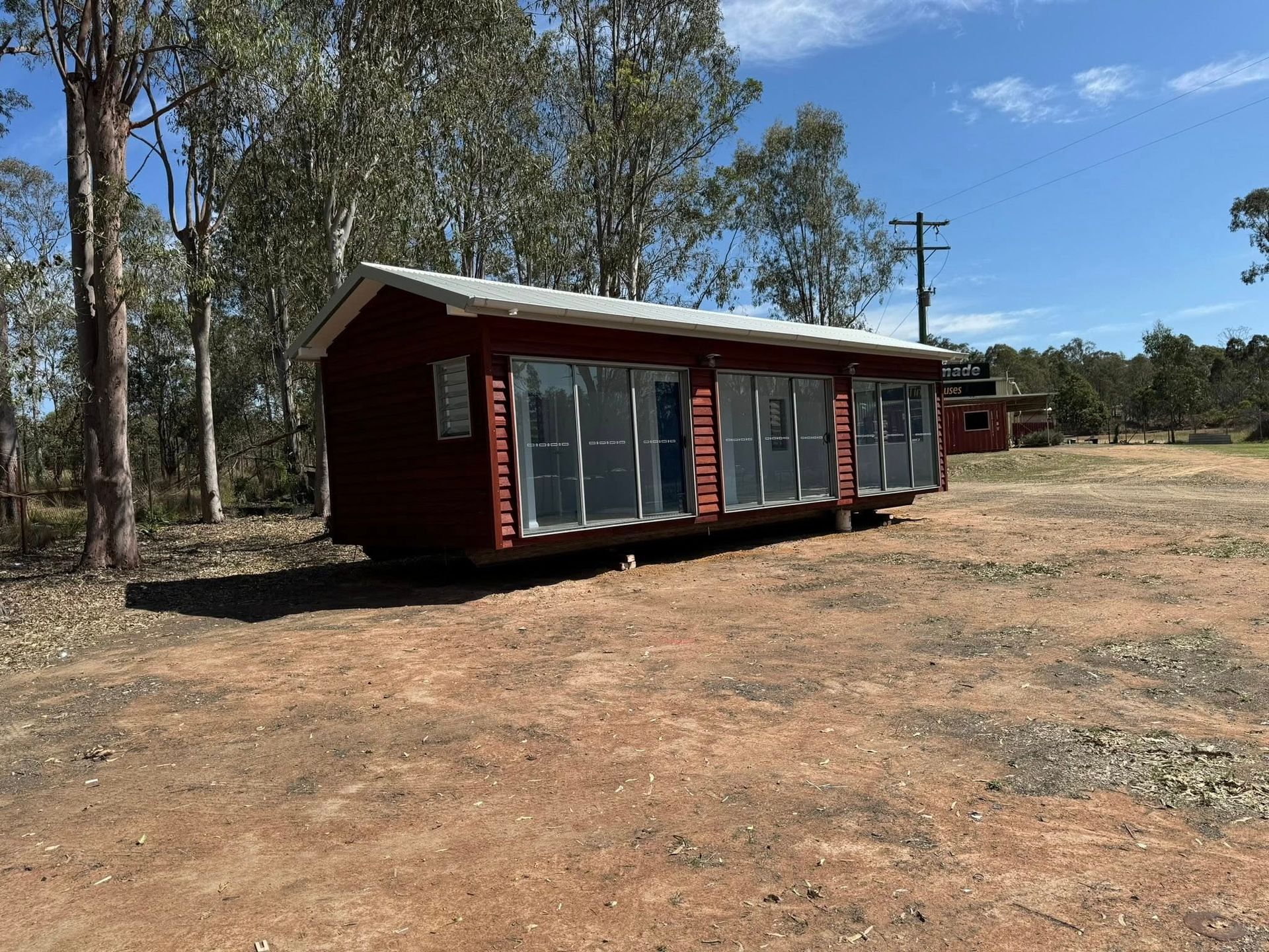 Red Cabin With Large Windows on a Dirt Clearing — Taylormade Constructions & Renovations In Kingaroy, QLD