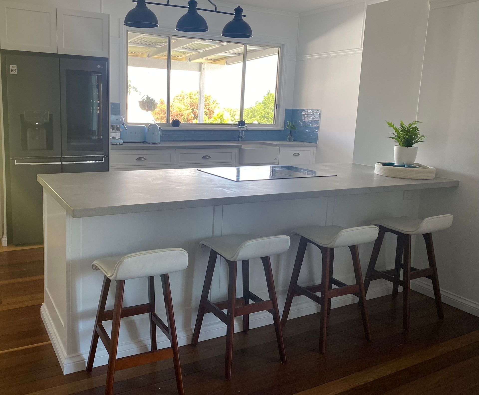 Kitchen With Island, Bar Stools, Pendant Lights, and Refrigerator — Taylormade Constructions & Renovations In Wooroolin, QLD