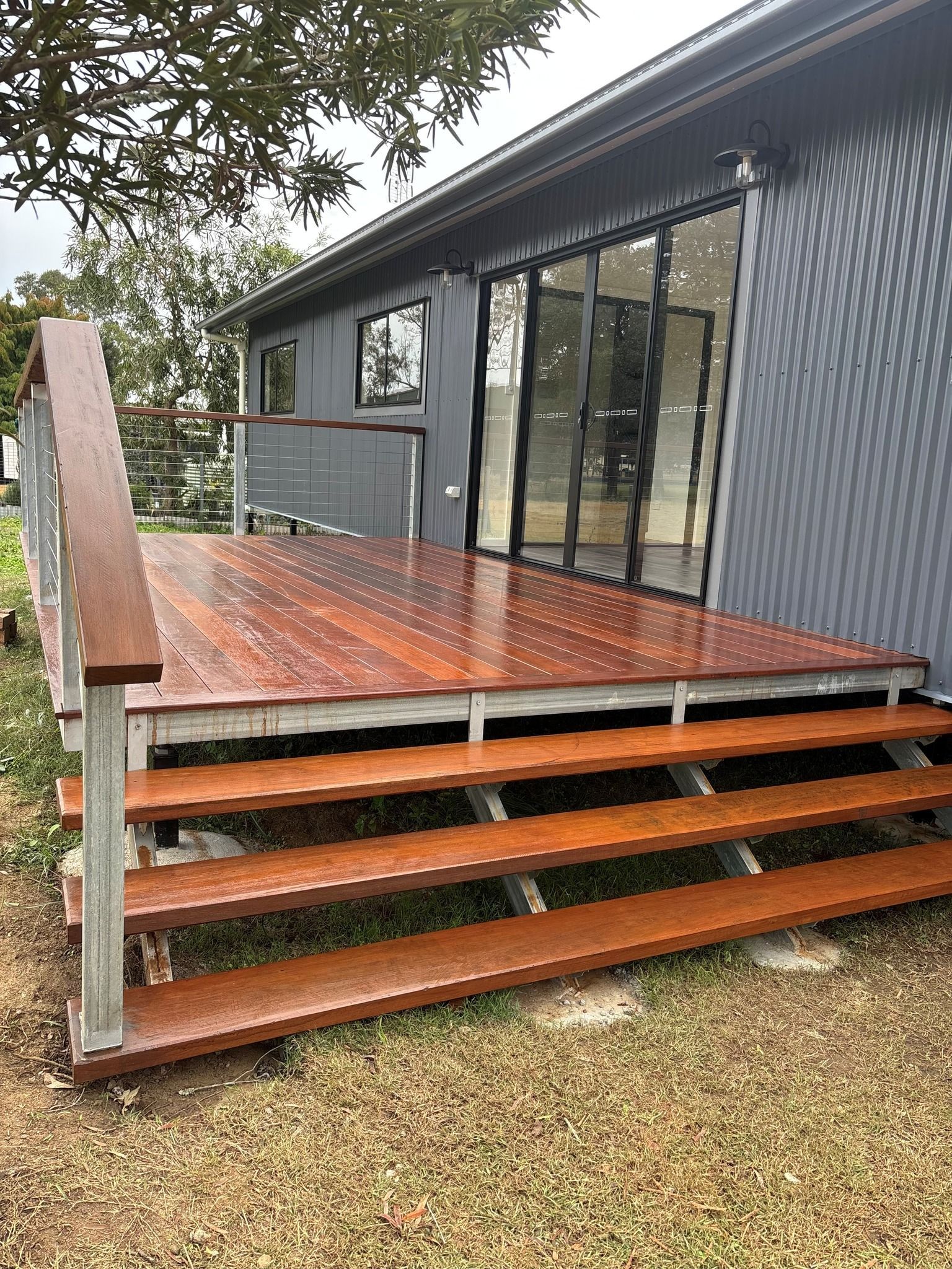 A Wooden Deck With Stairs, Leading to a Grey House — Taylormade Constructions & Renovations In Ellesmere, QLD