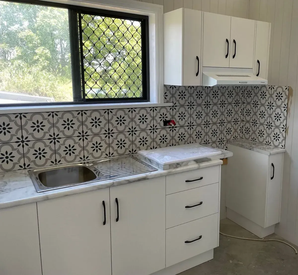 White Kitchen With Floral Tile Backsplash and Stainless Steel Sink — Taylormade Constructions & Renovations In Tarong, QLD