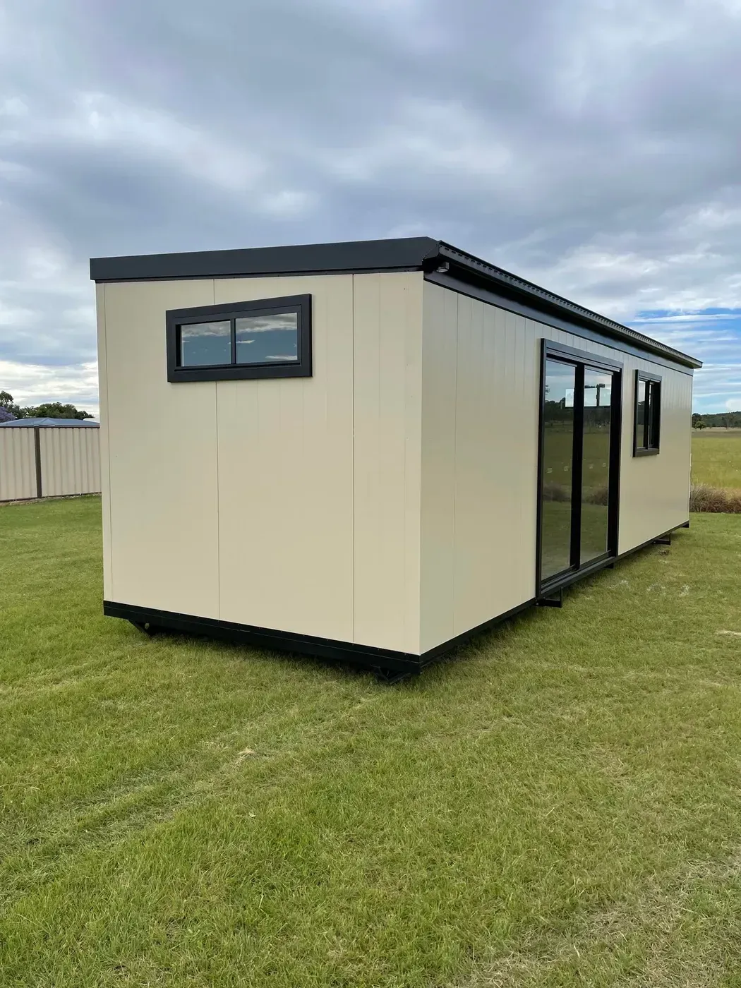 Beige Rectangular Portable Cabin on Green Grass With Sliding Glass Doors — Taylormade Constructions & Renovations In Blackbutt, QLD