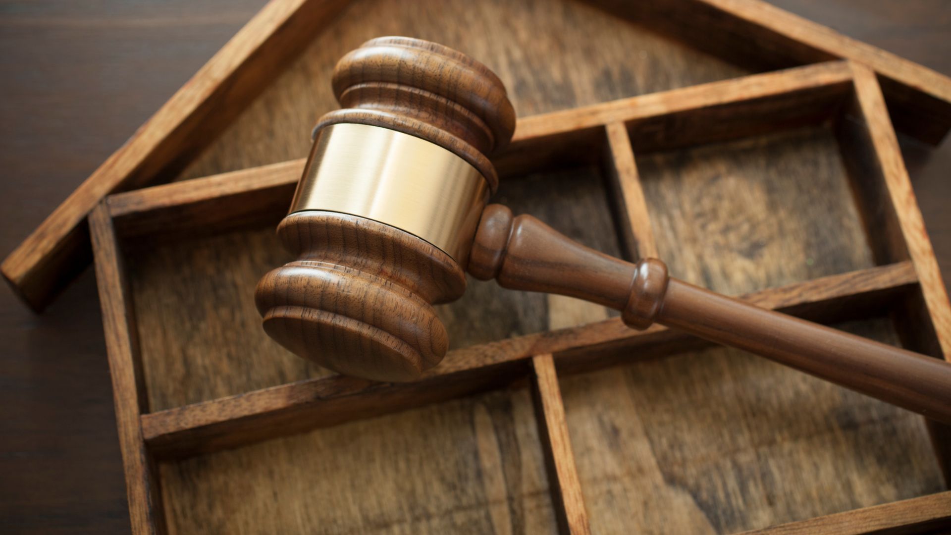 Wooden gavel resting on a wooden house-shaped structure, suggesting a legal matter related to property.