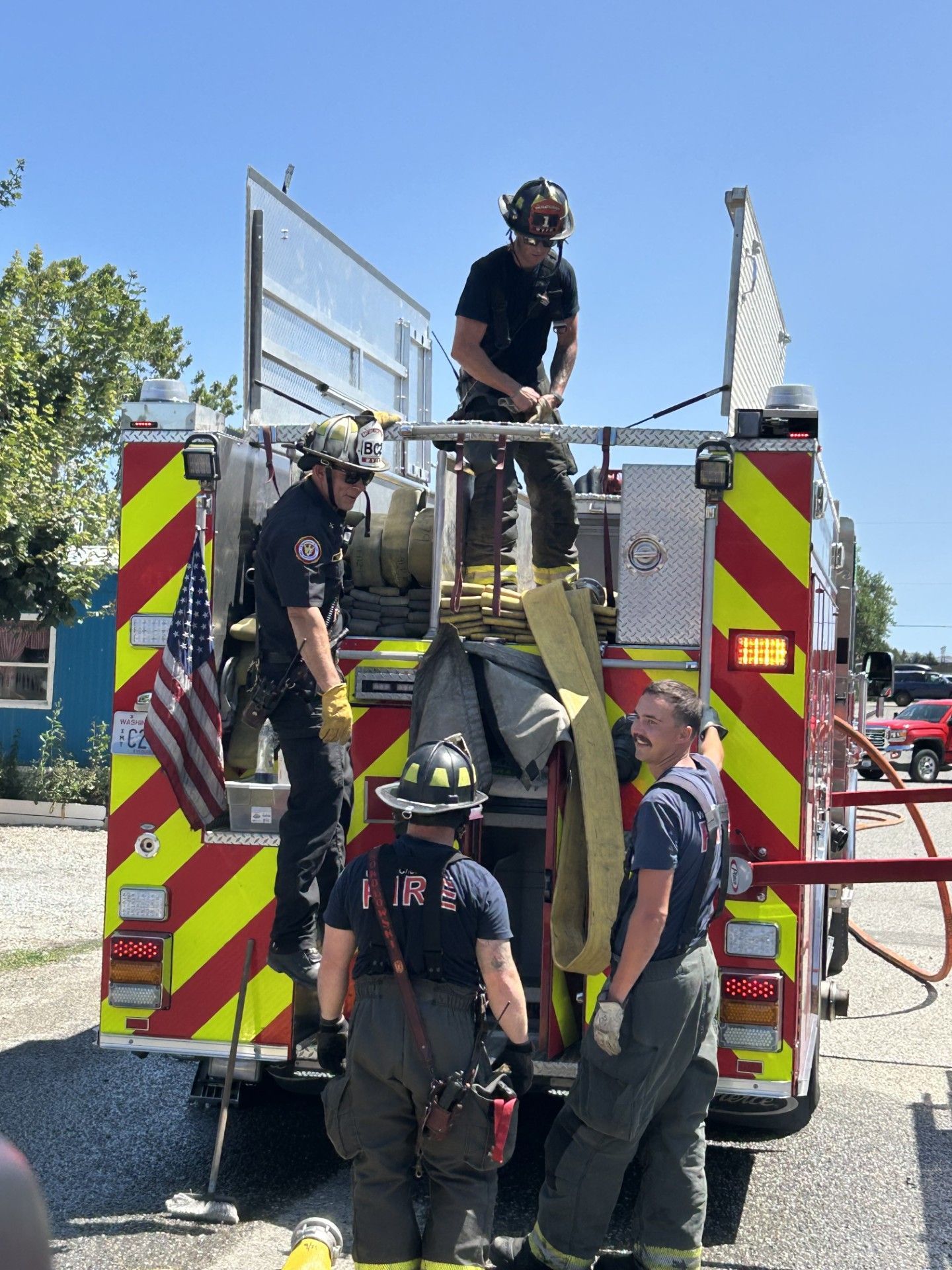 Firefighters on the back of a fire truck preparing equipment. 