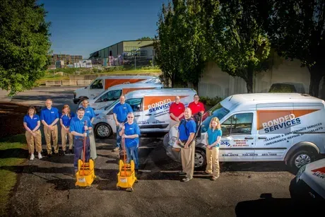 A group of people standing in front of a row of cleaning vans.