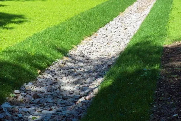 Yard drainage swale in MN designed to manage runoff and reduce water pooling in landscaped areas