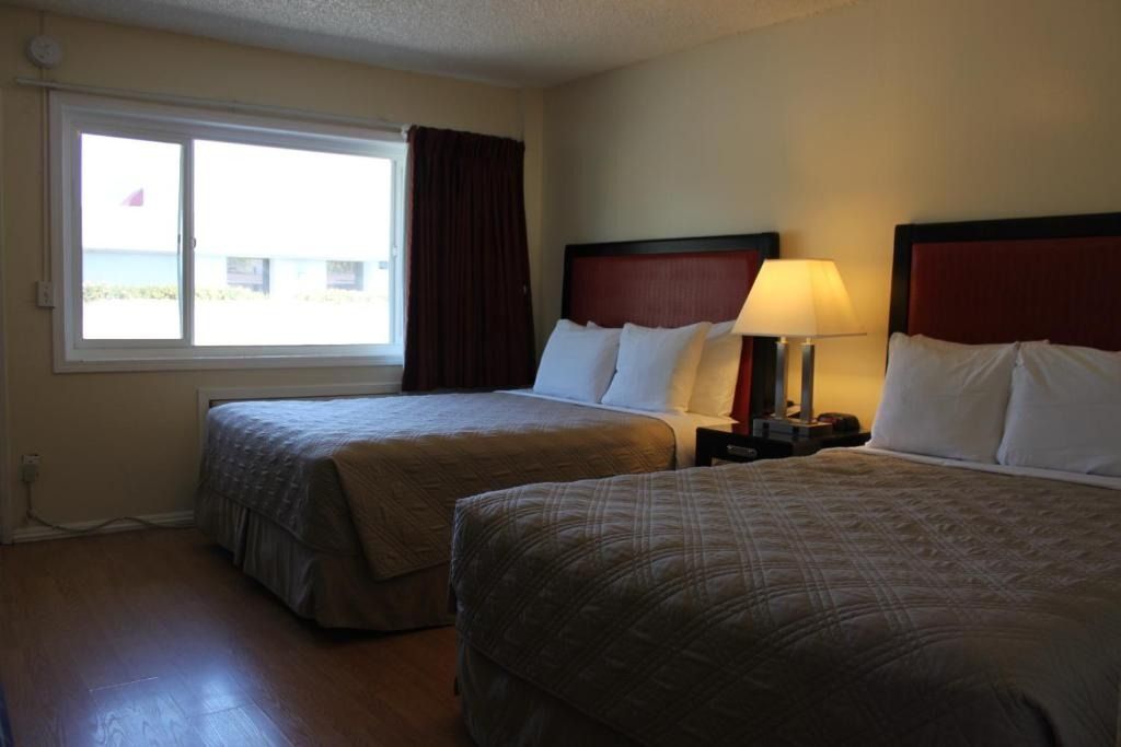 A hotel room with two beds and a window