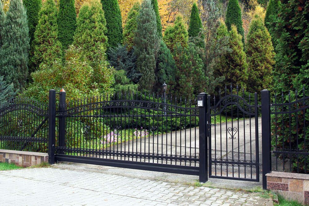A Black Wrought Iron Fence Surrounds A Driveway — Australian Advanced Fencing In Wauchope, NSW