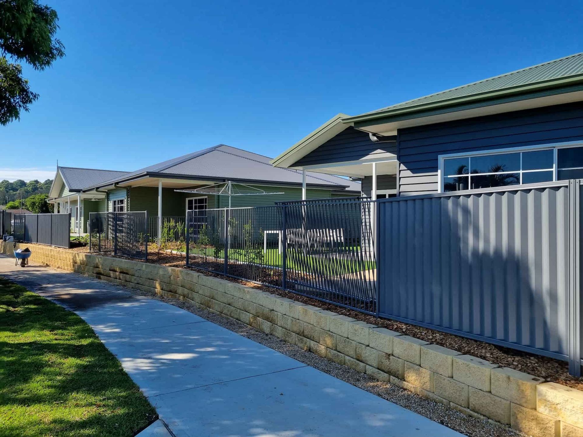 A Fence Surrounds A Row Of Houses On A Sunny Day — Australian Advanced Fencing In Port Macquarie, NSW