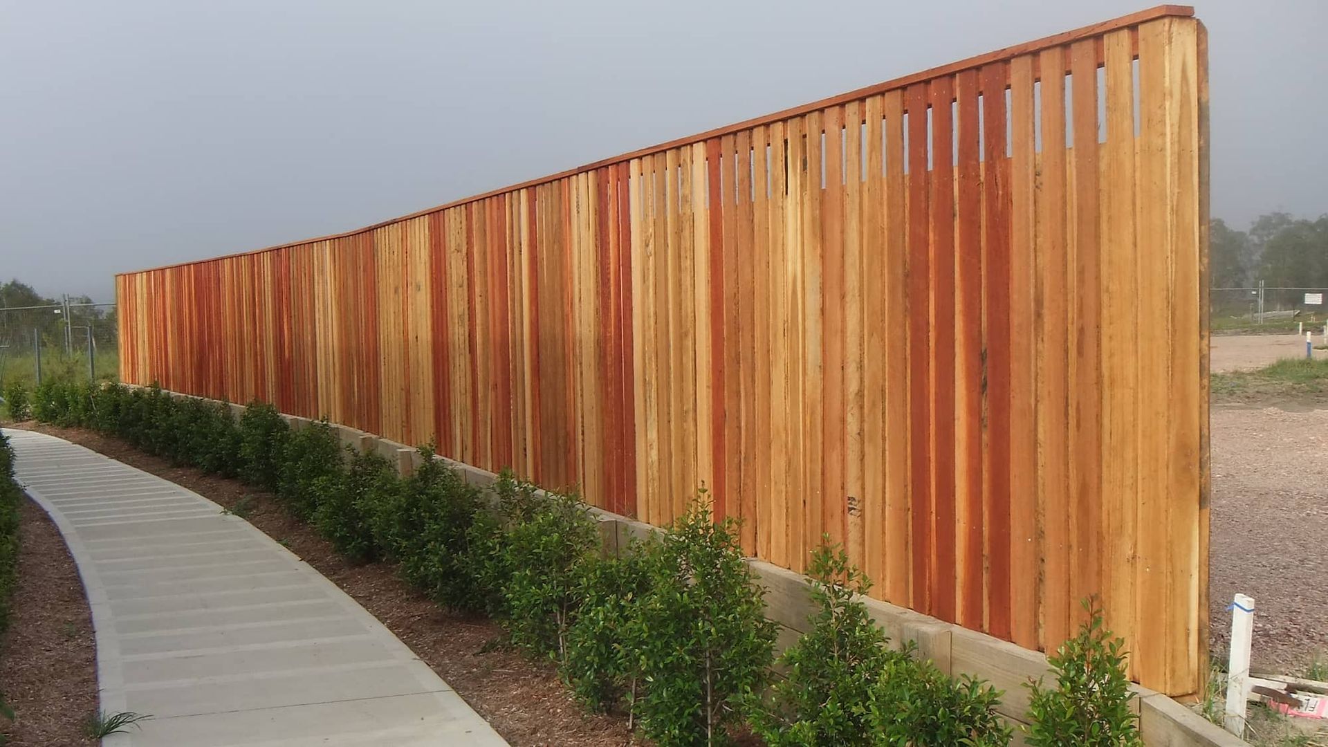 A Long Wooden Fence Surrounds A Concrete Walkway — Australian Advanced Fencing In Port Macquarie, NSW