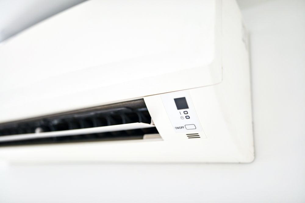 A White Air Conditioner is Hanging on a White Wall — FVS Airconditioning & Electrical Pty Ltd in Cloncurry, QLD
