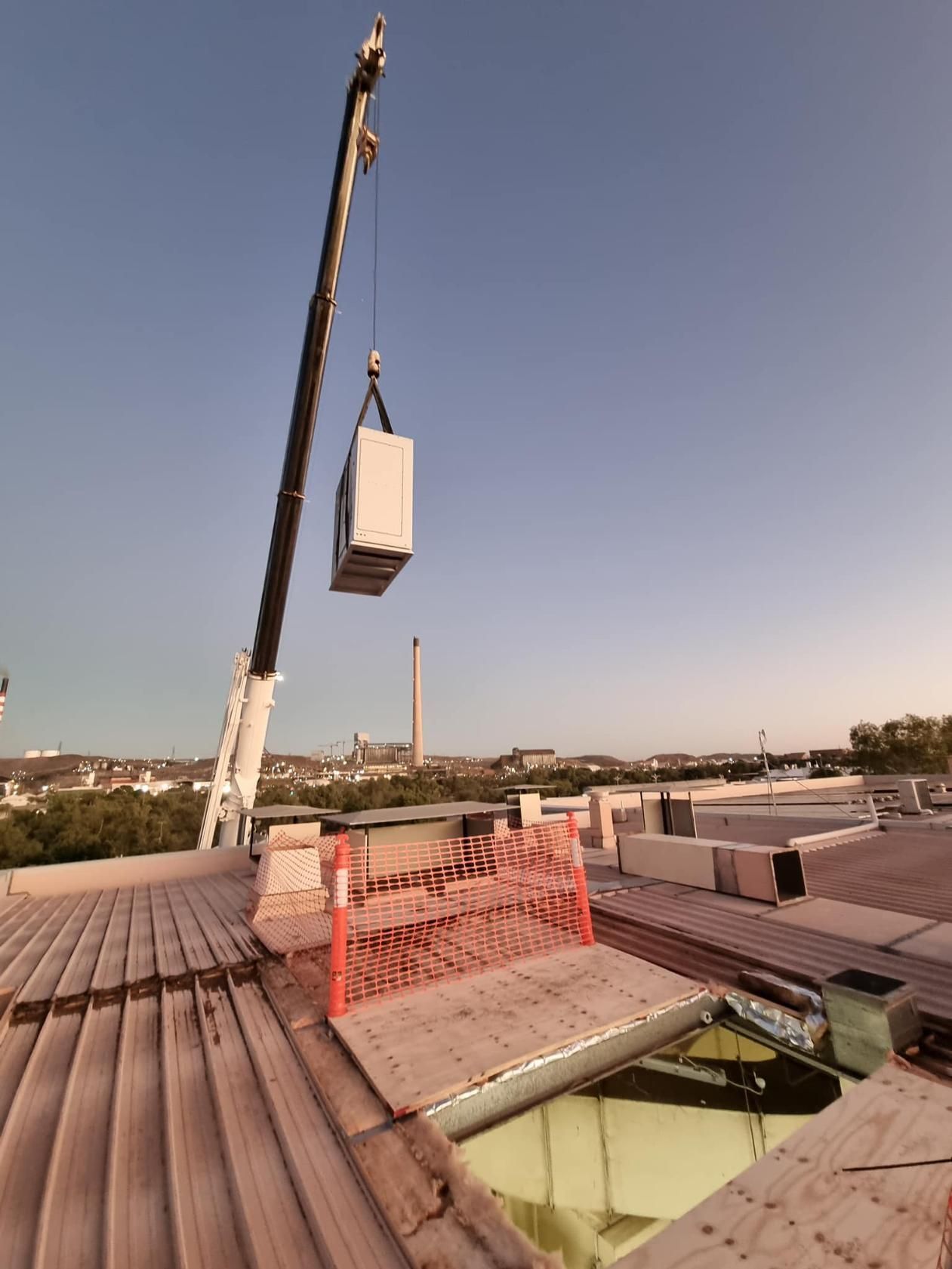 A Crane is Lifting a Box From the Roof of a Building — FVS Airconditioning & Electrical Pty Ltd in Cloncurry, QLD