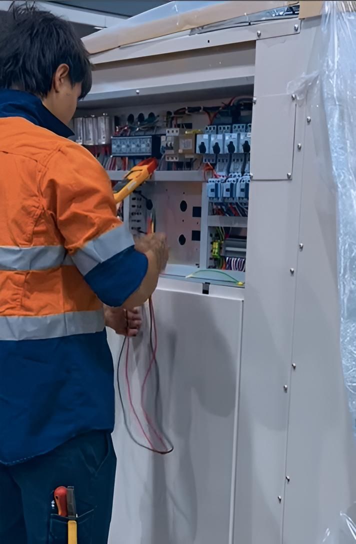 A Man in an Orange Shirt is Working on a Electrical Box — FVS Airconditioning & Electrical Pty Ltd in Ryan, QLD